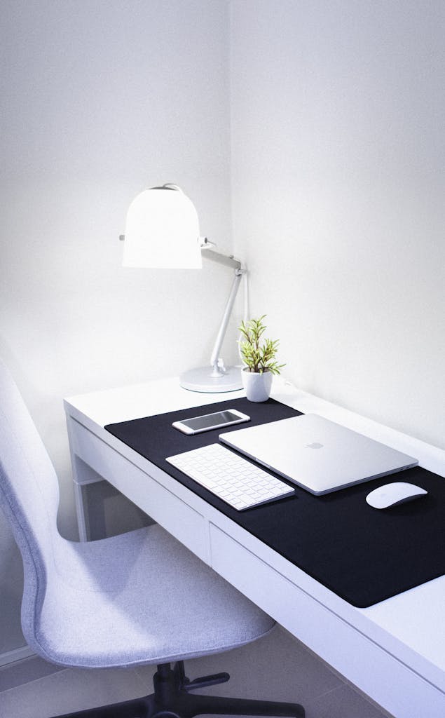 Sleek, modern home office setup featuring Apple devices, a desk lamp, and a plant.